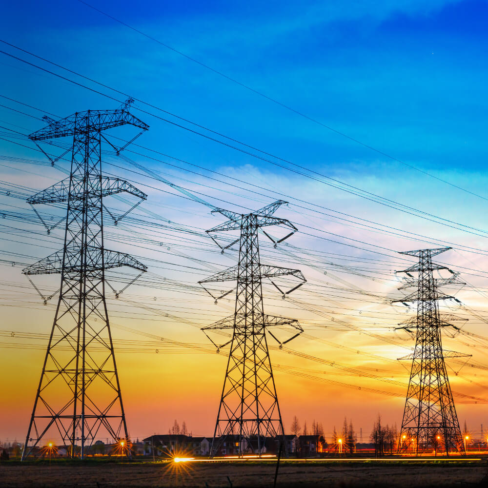 Silhouetted electricity towers against a vibrant sunset