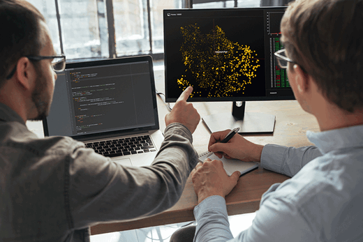 Two men looking at a data heatmap of the UK on a computer monitor